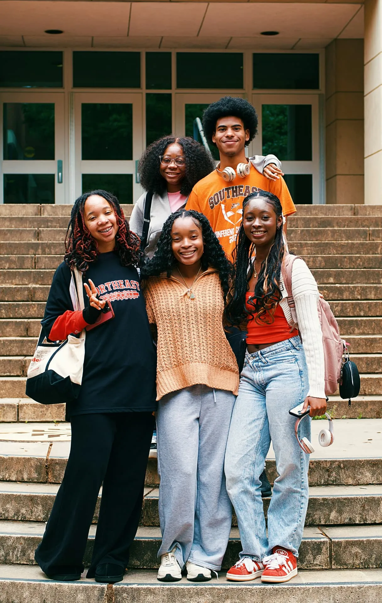Group of Black college-age friends smiling together outdoors.